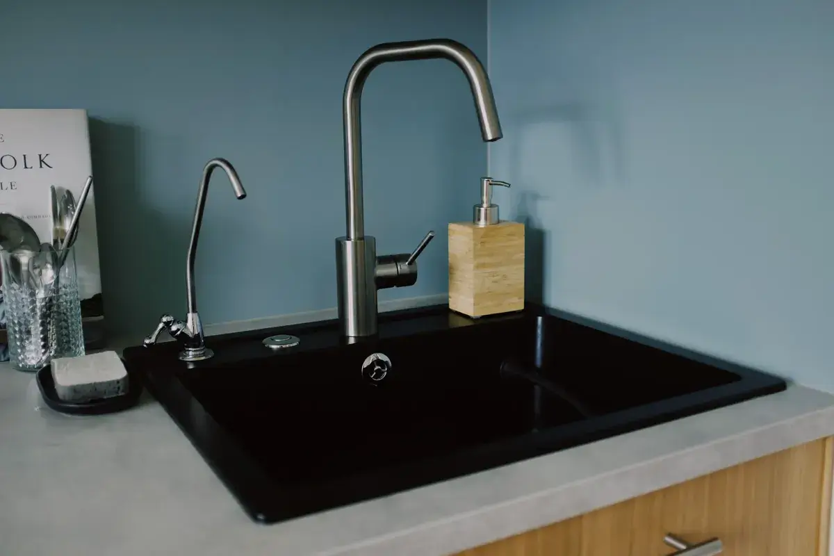 Évier de cuisine noir avec un grand mitigeur et, à sa gauche, un petit robinet mince réservé à l’eau potable.